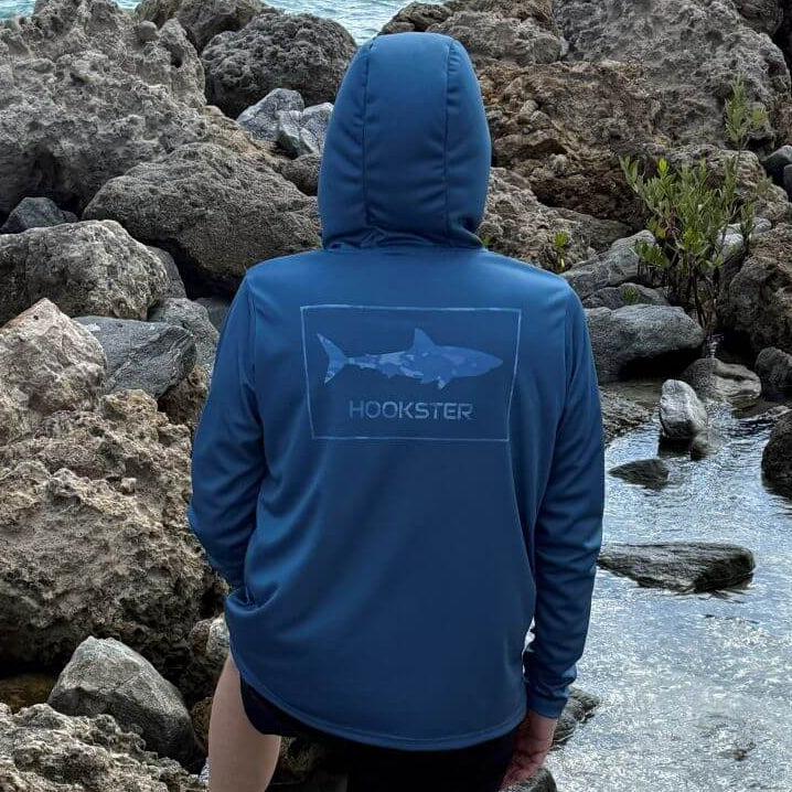 Back view of a man wearing the Apex Men's UV Hoodie in navy blue with hood up, standing outdoors