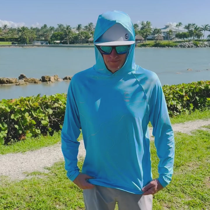 Video of an angler on the waterfront turning to show the front, back and thumbhole cuffs of the HOOKSTER Depth Lines UPF 50+ UV hoodie in blue with topographic contour lines