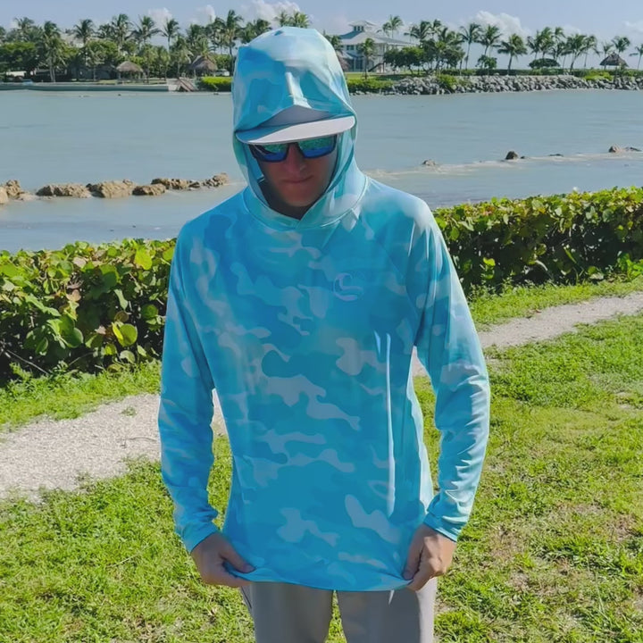 Video of an angler on the waterfront turning to show the front, back and thumbhole cuffs of the HOOKSTER Aqua Recon UPF 50+ UV hoodie in aqua and white camo