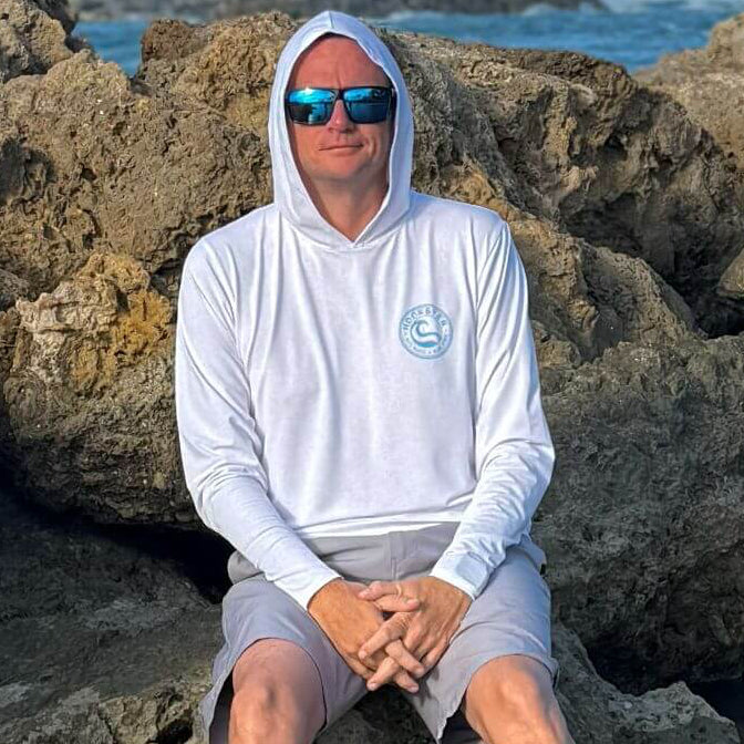 Man wearing the Reel Classic Men's UV Hoodie in white with hood down, standing outdoors